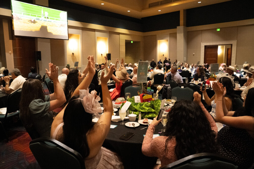 Guests cheering during C.A.M.P. University Night at the Races gala in the Rio Grande Valley