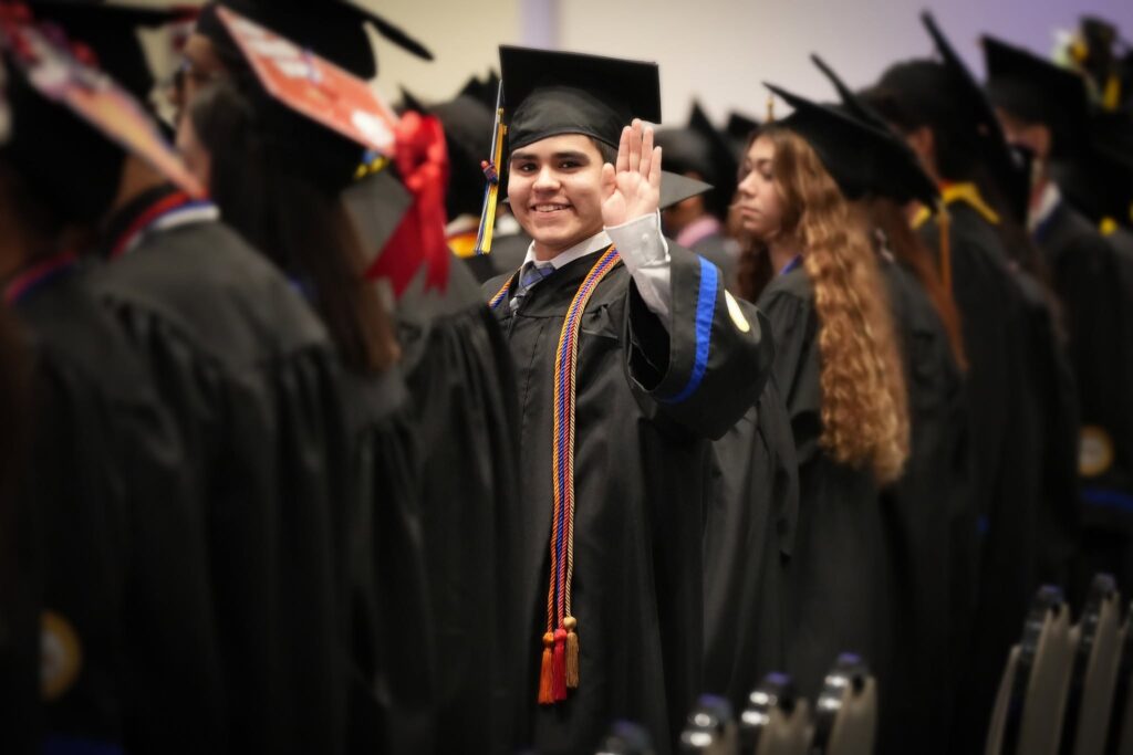 Idea North Mission High school graduate waving during graduation ceremony