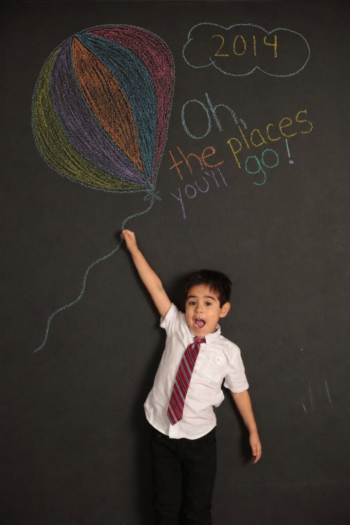 Child standing in front of chalkboard graduation photo